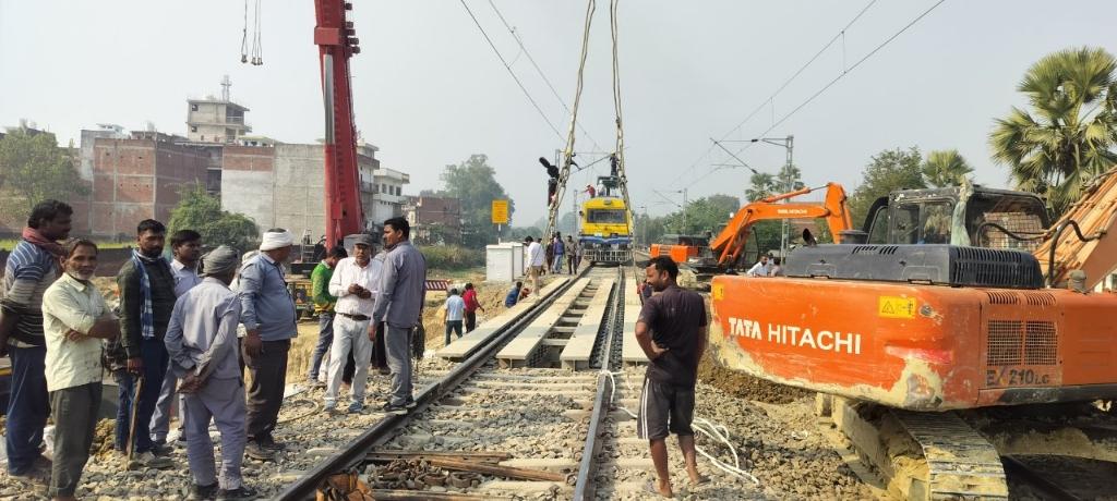 खुरासन रोड। आजमगढ़ जिले के फूलपुर कस्बा स्थित गेट संख्या 55 सी और 56 सी  के मध्य बन रहे अंडर पास निर्माण में तेजी आ गई है। निर्माण की गति और तेज करते हुए  रविवार को अप रेलवे लाइन को गर्डर से उठा कर हटा दिया गया है अब इसके स्थान नई रेल पटरी लगा दिया गया है। रेलवे लाइन के नीचे कार्य पूरा  कर दिया गया है। इसके लिए रविवार को तीन घंटे के लिए अप लाइन ब्लाक की गई थी। गडर से लाइन उठाने के बड़े बड़े क्रेन लगाए गए थे। लाइन के नीचे गिट्टी डालने के लिए तीन जेसीबी और फोक लैंड मशीनें लगाई गई थी। मौके पर बिजली सप्लाई काटने के लिए ओ एच ई निरीक्षण यान बुलाया गया था। रोडवेज के पास से होकर शाहगंज   - आजमगढ़ -  मऊ रेल मार्ग गुजरता है। रेल लाइन की दोनों तरफ बसी आबादी को आ वा ग मन में परेशानी न हो इसके लिए नगर के बीच पड़ने वाले इस रेल लाइन  पर रेलवे की तरफ से समपार फाटक बनाया गया है। इस रास्ते जब भी कोई ट्रेन आती है तो नगर में तीनों रेलवे ढाले एक साथ बंद हो जाते हैं। इससे कस्बा दो हिस्सों में बंट जाता है। रेलवे समपार फाटक बंद होने के दौरान दोनों तरफ से छोटे-बड़े वाहनों की लंबी कतार लग जाती है, जिससे जाम की स्थिति बन जाती है। लोगों को जाम से निजात दिलाने और फूलपुर नगर से पौराणिक  स्थल दुर्वासा धाम और उसके आस पास गांव तक जाने के  लिए रेलवे की तरफ से रोडवेज के पास  अंडर पास का निर्माण कराया जा रहा है। निर्माणाधीन अंडर पास के निर्माण कार्य में तेजी आई है। खुरासन रोड सहायक स्टेशन मास्टर शंभू सिंहा  ने बताया कि अंडर पास के पास अप लाइन को सही करने के लिए तीन घंटे के लिए रेल लाइन को ब्लाक किया गया है।