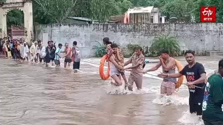 Devotees Trapped In Ashram, सवाई माधोपुर जिले में लगातार जारी बारिश के कारण सोमवार को डिग्गी कल्याण यात्रा के लिए जा रहे श्रद्धालुओं का जत्था जतिधाम आश्रम में फंस गया. सूचना के बाद पुलिस और सिविल डिफेंस की टीम ने स्थानीय लोगों की मदद से सभी श्रद्धालुओं को आश्रम से सुरक्षित बाहर निकाला. वहीं, पानी के तेज बहाव में बहने से एक महिला की मौत हो गई.